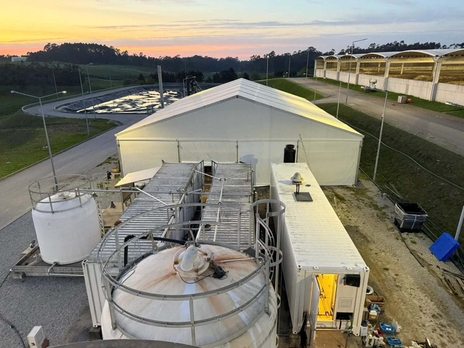 Deponiesickerwasser-Anlage mit Zelthalle, Containern und Sickerwasserbecken bei Sonnenuntergang in Portugal
