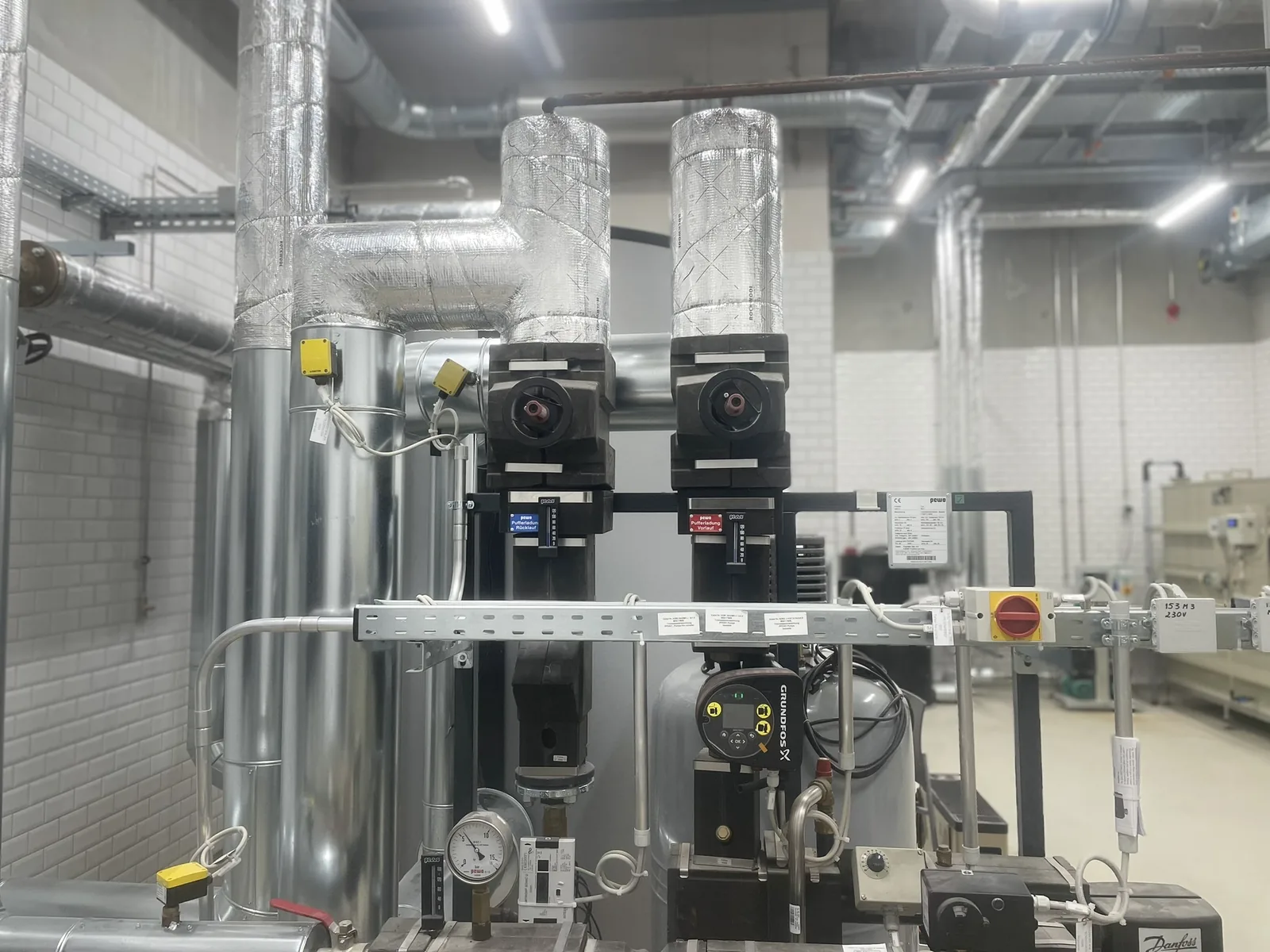 Isolierte Leitungen mit Regelventilen und Pumpen im Technikraum am Flughafen Frankfurt